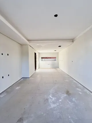 Corredor longo e vazio com piso claro e teto branco.