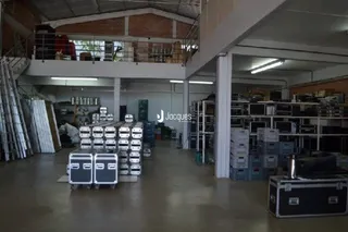 Interior de um espaço industrial com estantes de metal e materiais de construção.
