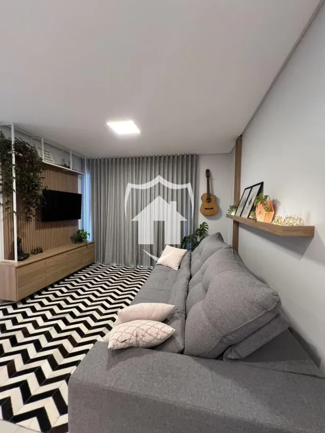 Sala de estar com sofá cinza e tapete preto e branco.