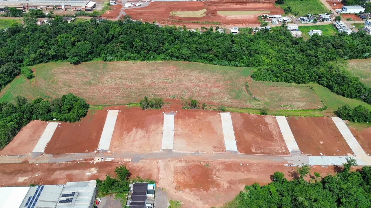 Vista aérea de um terreno aberto com áreas de vegetação e solo avermelhado.
