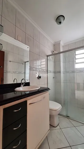 Foto de um banheiro com revestimento de azulejos brancos e box de vidro.
