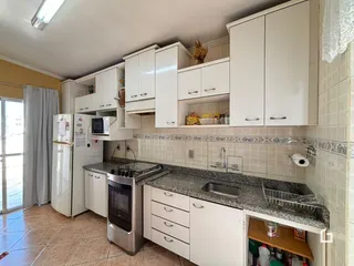 Cozinha com armários brancos e bancada de granito.