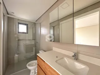 Um banheiro moderno com box de vidro e bancada de madeira.
