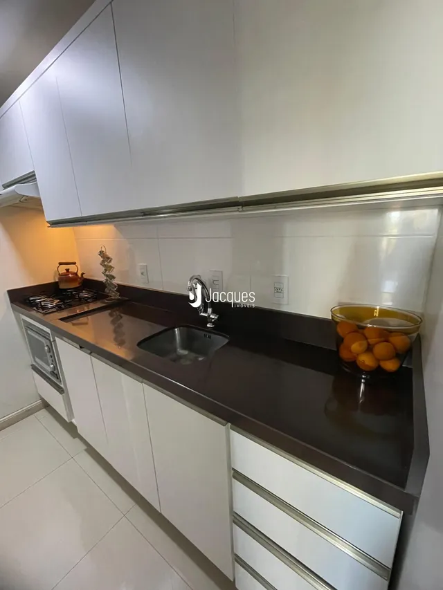 Foto de uma cozinha com armários brancos e bancada escura.