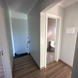 Foto de um corredor interno com piso de madeira clara.