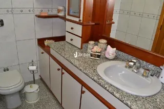 Foto de um banheiro com bancada e armários de madeira.