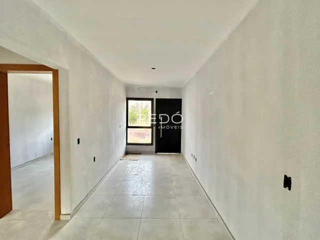 Foto do corredor interno de uma residência com piso de cerâmica clara.
