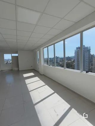 Ambiente interno com grandes janelas que oferecem vista para a cidade.