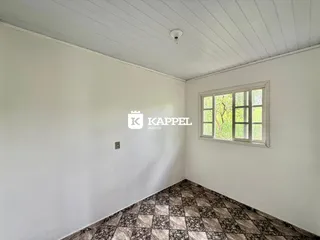 Foto de um cômodo interno com paredes brancas e piso de azulejos escuros.