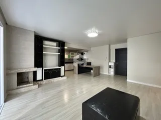 Sala de estar com piso de madeira clara e lareira no interior da residência.