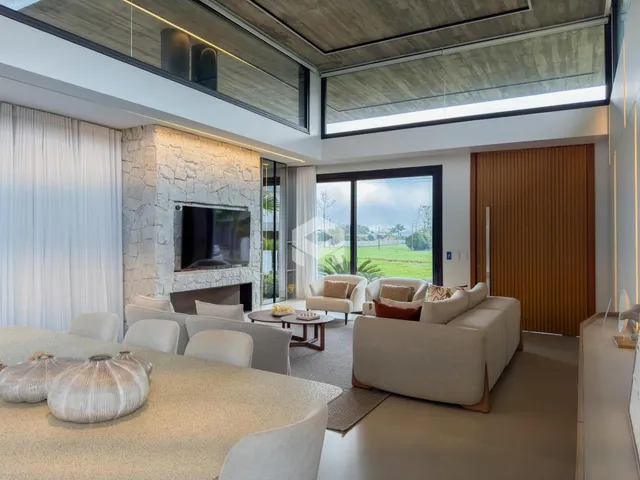 Sala de estar moderna com grandes janelas e decoração clara.