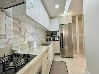 Cozinha moderna com armários brancos e bancadas claras.