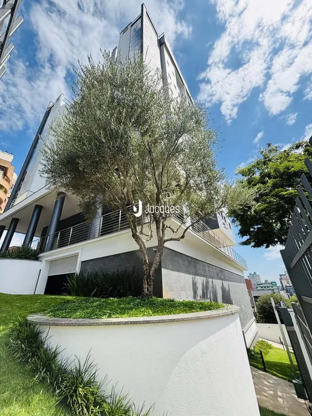 Fachada moderna de um edifício residencial com uma árvore em primeiro plano.
