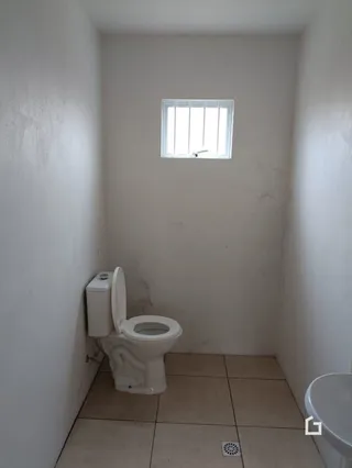Foto de um banheiro interno com parede branca e janela.
