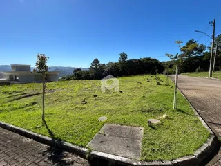 Vista externa de um terreno gramado com uma casa ao fundo.