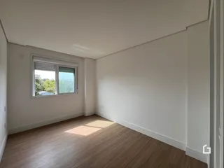 Sala de estar com piso de madeira e janela iluminada.