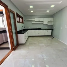 Foto de uma cozinha com armários brancos e piso claro.