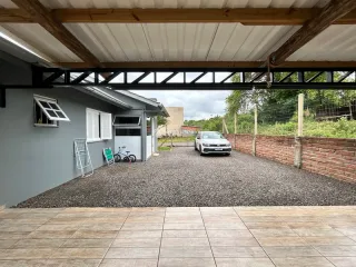 Vista da área externa com piso de lajotas e muro de tijolos.