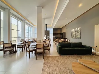 Ambiente interno de uma sala de jantar ampla com grandes janelas.