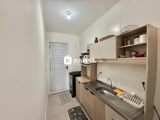 Foto de uma cozinha com bancada e armários brancos em um apartamento.