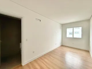 Ambiente interno com piso de madeira clara e paredes brancas.