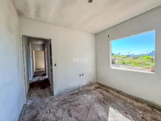 Interior de um corredor com paredes brancas e piso de concreto cru.
