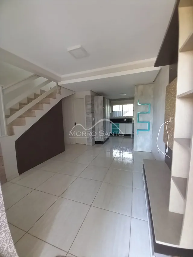 Hall de entrada com escadas e piso de cerâmica claro.