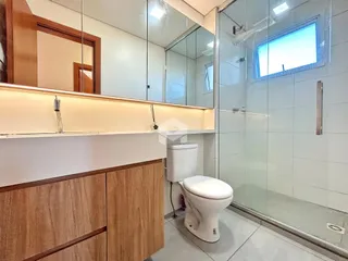 Banheiro com box de vidro e armários de madeira.