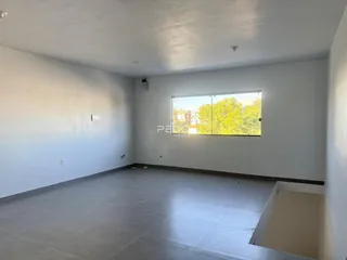 Ambiente interno de uma sala ampla com piso de cerâmica e grande janela.