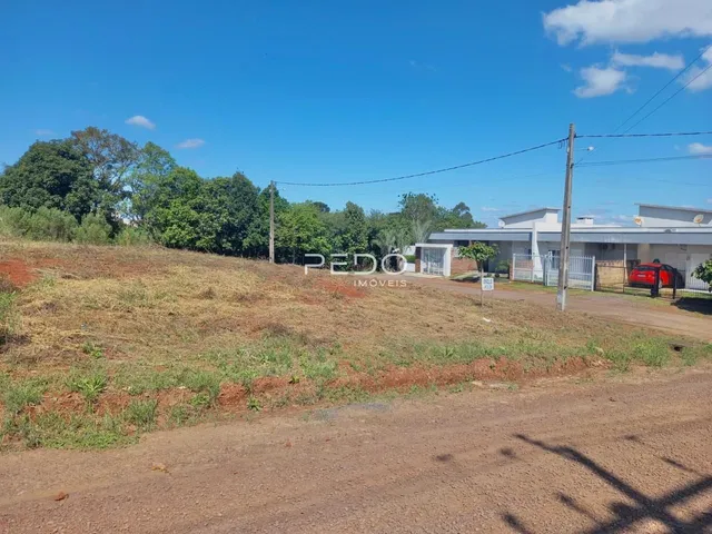Vista externa de uma propriedade com terreno gramado e uma construção ao fundo.