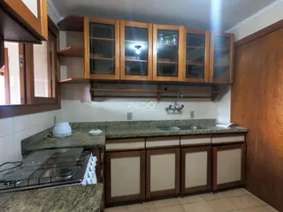 Vista da cozinha com armários de madeira e bancada.