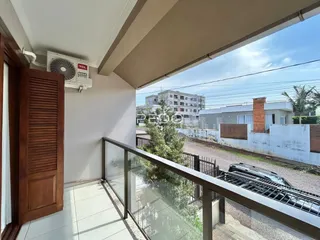 Vista da varanda com grade de vidro e paisagem urbana.