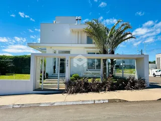 Foto da fachada de uma casa moderna branca com jardim em Lajeado.