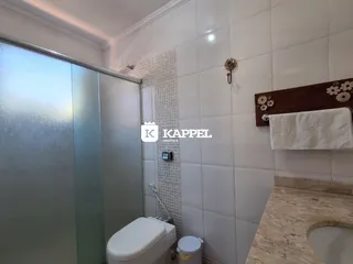 Banheiro com revestimento de azulejos brancos e box de vidro.