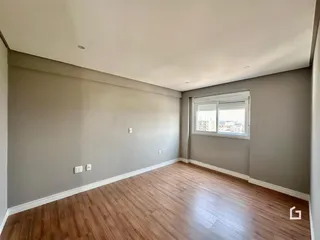 Sala de estar com piso de madeira e parede cinza clara.