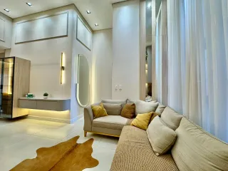 Sala de estar com sofá grande e cortinas brancas.