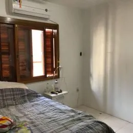 Foto de um quarto com cama coberta por um edredom xadrez e janela de madeira.