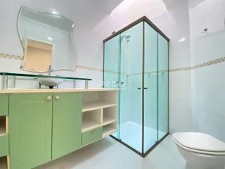 Foto de um banheiro moderno com box de vidro e armário verde.