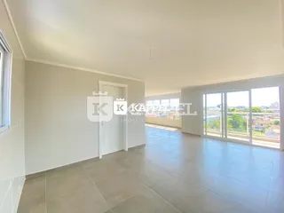 Ambiente interno com piso de cerâmica e grandes janelas na sala.