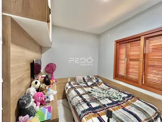 Quarto com cabeceira de madeira e janela com persianas.