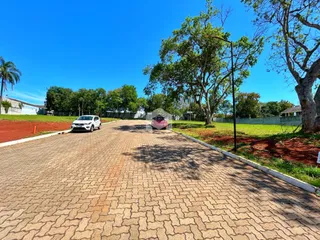 Vista da entrada de uma propriedade com calçada pavimentada e vegetação ao fundo.