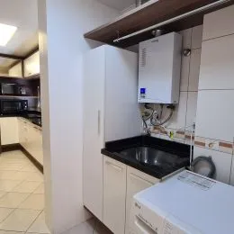 Foto de uma cozinha com armários brancos e bancada escura.