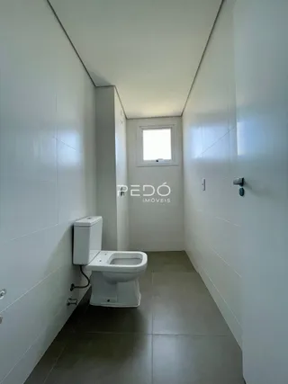 Foto de um banheiro com vaso sanitário em um corredor claro.
