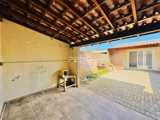 Vista de uma área externa coberta com piso de cerâmica e estrutura de madeira.