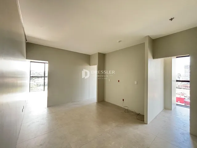Interior de uma sala com paredes brancas e piso de concreto claro.