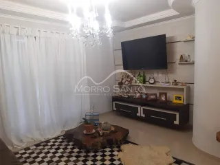 Uma sala de estar com paredes brancas, cortinas brancas e um móvel de madeira escura.