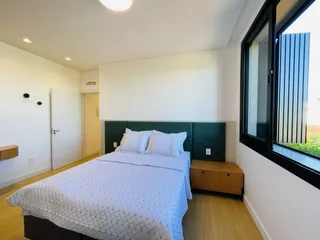 Quarto com cama e janela de grande porte.