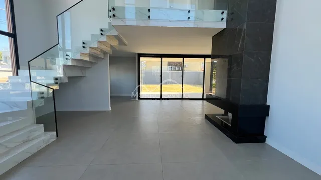 Área comum com escadaria de vidro e portas de correr que dão acesso ao jardim.