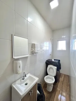 Foto de um banheiro com azulejos brancos e piso de madeira.