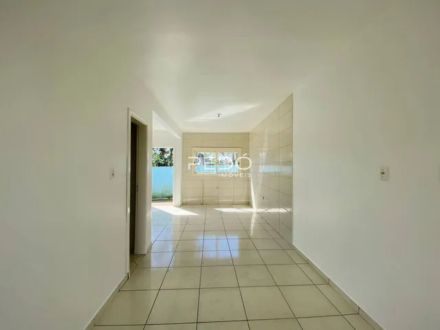 Corredor interno com paredes brancas e piso de cerâmica em uma residência.